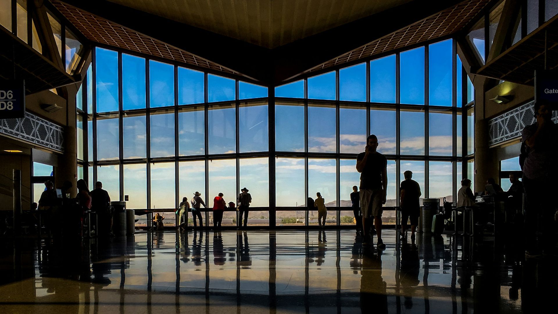 Travellers moving through a sunlit international airport terminal at dawn